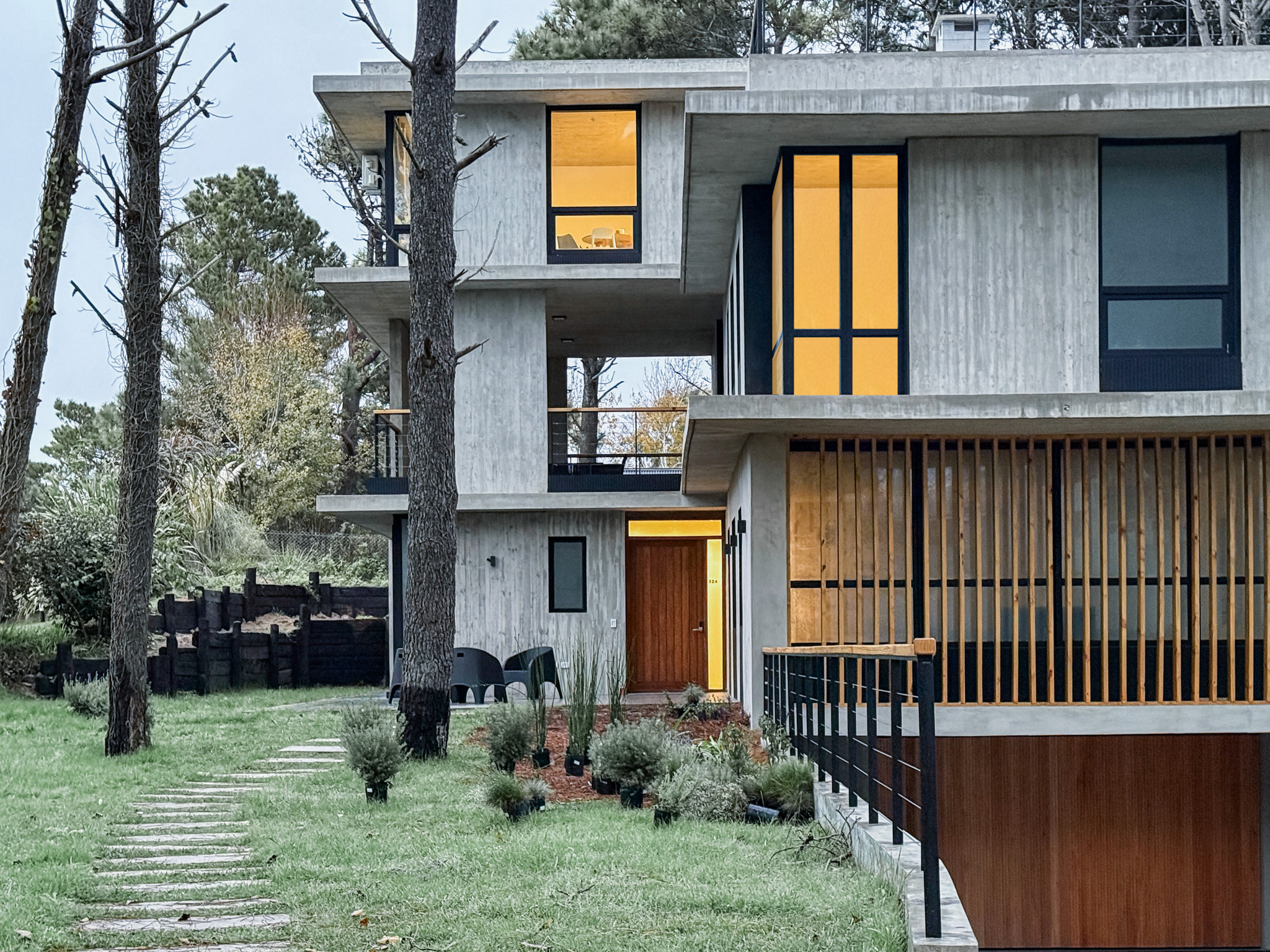 IL BUCO modern villa exterior with warm lighting and pine forest