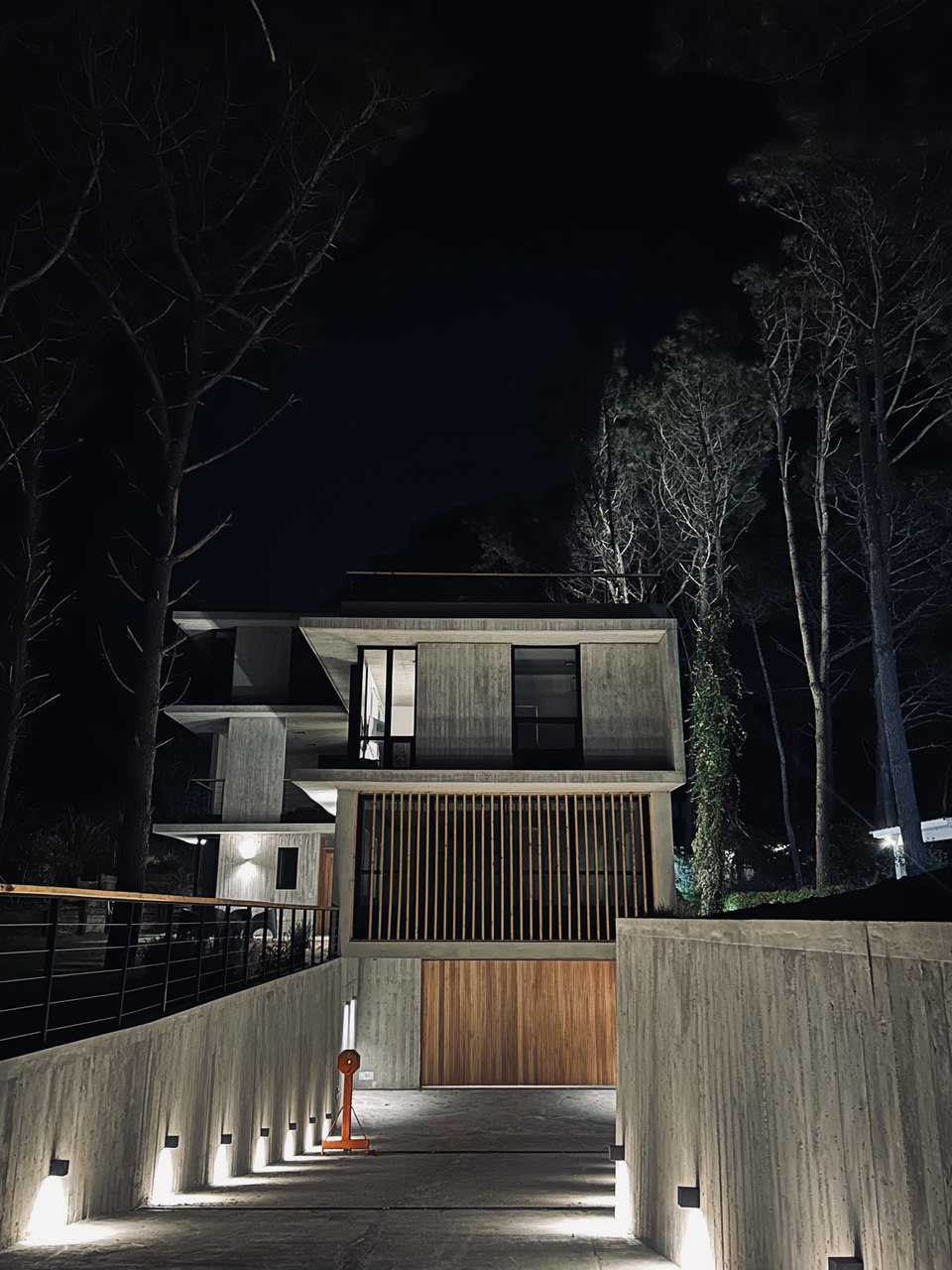 Villa IL BUCO iluminada de noche entre bosque de pinos en Cariló